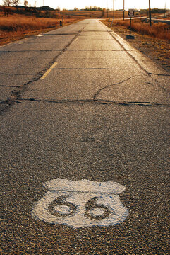 The symbol for the historic Route 66 is painted on the highway and seen in the sunset reflections