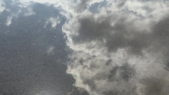 Cloud reflection on wet asphalt surface, abstract water reflection background