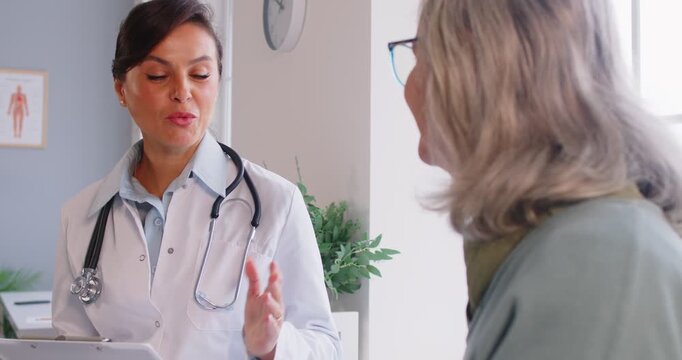 Kind doctor, caring nurse talking to senior mature patient meeting in hospital, alzheimer caregiver wearing uniform comforting and supporting elder woman on treatment giving empathy and care help