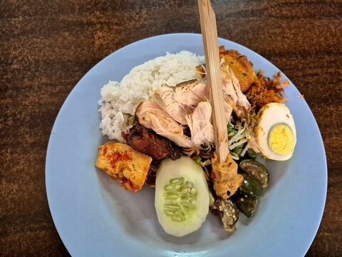 Indonesian mixed rice with chicken, egg, tofu and vegetables, authentic local street food plating