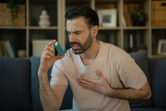 Young man experiencing asthma attack using inhaler for relief