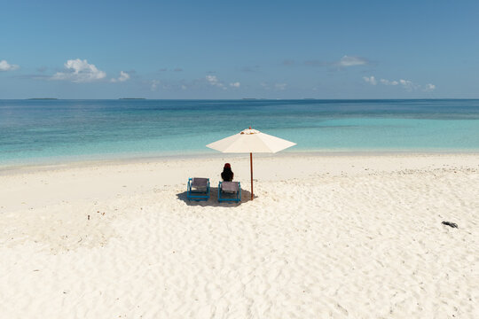 Young woman relaxing under umbrella on the beach in the Maldives