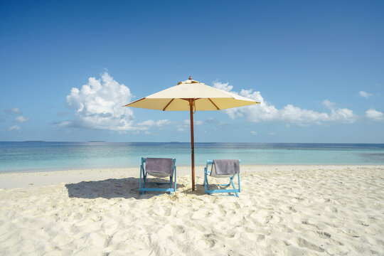 Umbrella and two chairs on a sandy beach in the Maldives