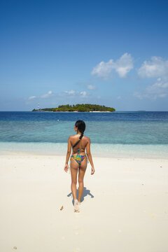 Young asian woman in bikini walking on the beach in the Maldives