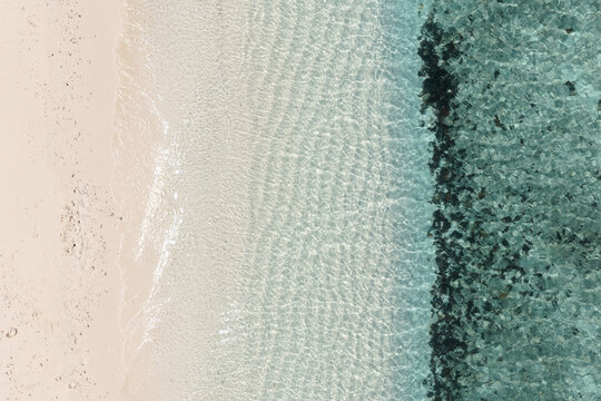 Aerial top down view of white sand beach and ocean in the Maldives