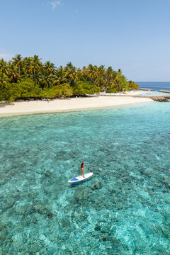 Aerial view of asian woman stand up paddling in the ocean, Maldives