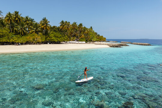 Aerial view of asian woman stand up paddling in the ocean, Maldives