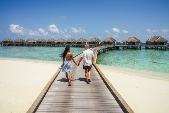 Romantic couple walking hand in hand on jetty, Maldives islands