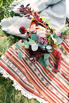 Charming bouquet of succulents and proteas arranged outdoors on striped rug