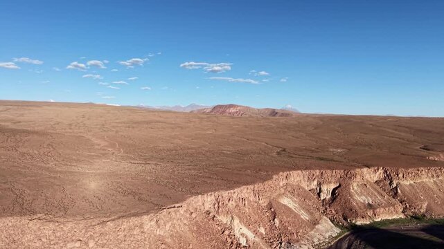 Cinematic aerial flying forward toward the vibrant green, red, and white mineral-rich mountains of Valle del Arcoiris near San Pedro de Atacama at sunset