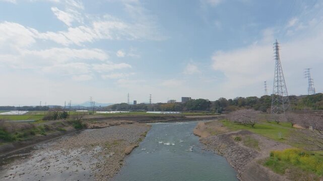 Scenic view of a river with a row of high-voltage electric pylons and power lines on the banks