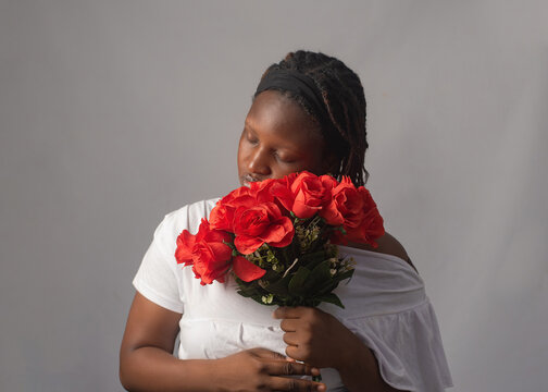 Young African Woman Leaning Head on Red Rose Bouquet