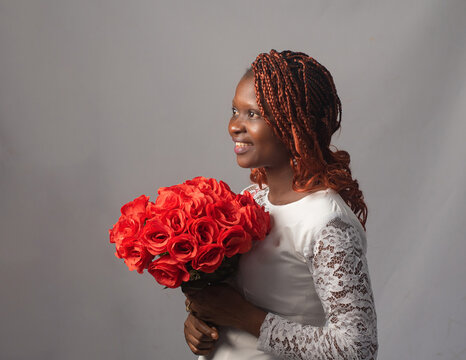 Smiling Nigerian Woman in Lace Top and Red Braids Holding Rose Bouquet