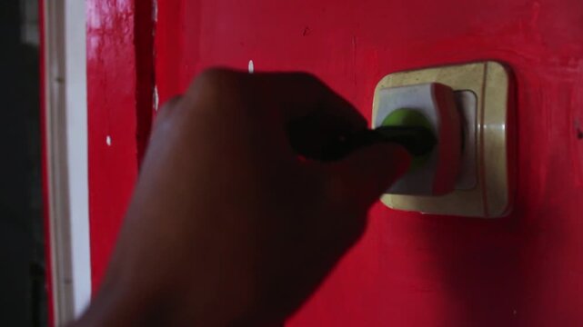Hand Plugging Power Cord into Electrical Outlet on Red Wall &ndash; Daily Home Activity