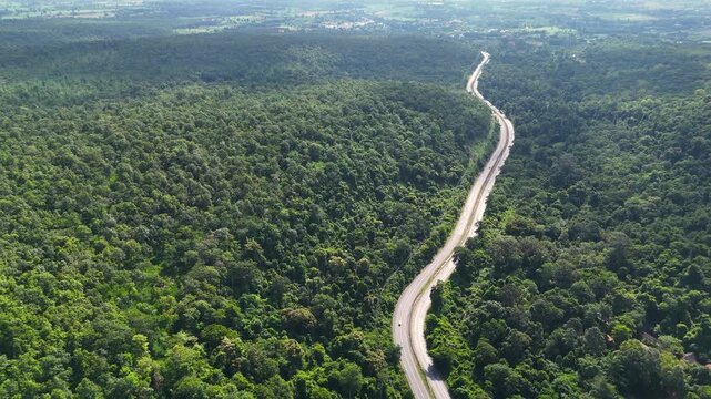 High-angle drone footage of a winding mountain road cutting through dense green forest, capturing natural landscape, scenic travel route, and peaceful countryside environment from above.