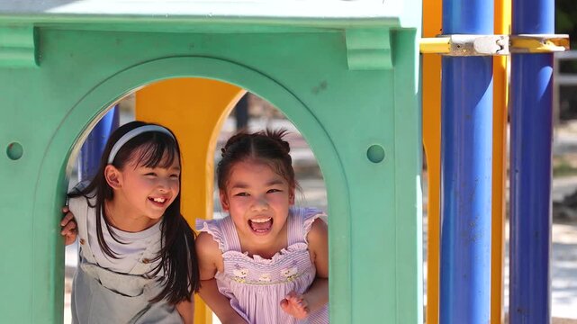 Two Happy Young Asian Girls Laughing and Playing at Outdoor Playground