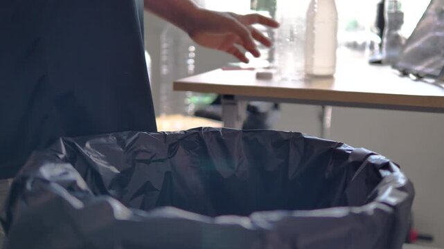 Person placing plastic bottle into recycling bin in modern home. Waste sorting, sustainability and environmental responsibility concept