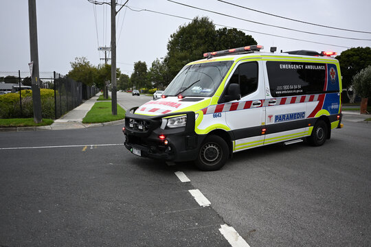 Ambulance Victoria paramedic vehicle, a Mercedes Benz Sprinter van, turning into a side street in suburban Melbourne as its lights flash red