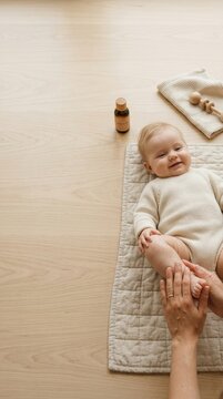 A caregiver plays with a baby by massaging the baby's feet while resting on a mat in a room