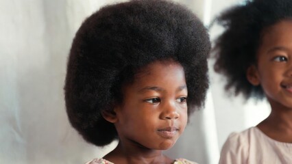 Obraz premium Young child with afro hairstyle looking thoughtful indoors