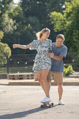 Obraz premium Happy couple learning skateboarding together in sunny urban setting