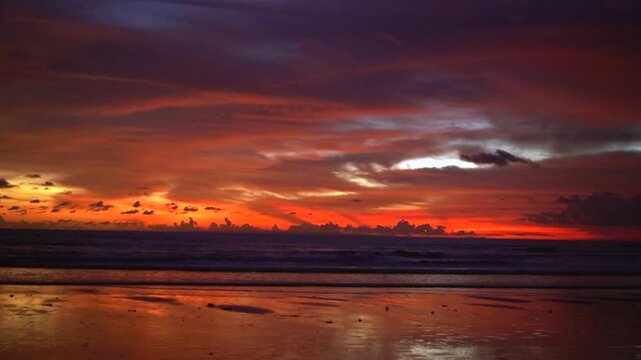 Vivid Red Sunset Clouds Reflected on Wet Sand at Kelating Beach
