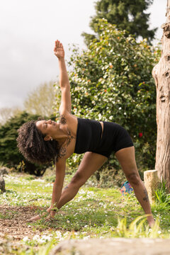 Woman practicing triangle pose yoga outdoor in nature