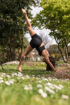 Woman practicing three-legged downward dog yoga pose outdoors