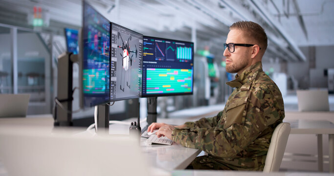 Engineer Oversees Military Drone Manufacturing Process Via Multiple Computer