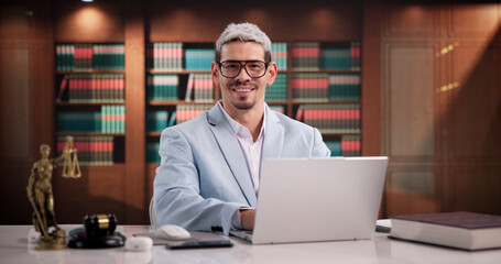 Naklejka premium Cheerful Hispanic Male Attorney In Office Surrounded By Legal Books