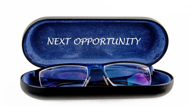 Blue framed reading glasses sit in an open blue velvet lined case, showcasing the uplifting message Next Opportunity on the soft interior surface
