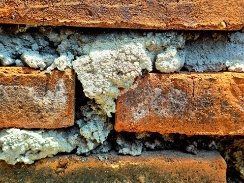 Extreme close-up of red brick texture with thick grey cement mortar.