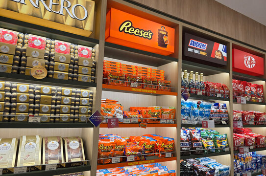 Changi, Singapore - Jan 14, 2026: Various retail shelves featuring Nestl&eacute; KitKat, Snickers, Reese's, and Ferrero Rocher chocolate products at a duty-free store.