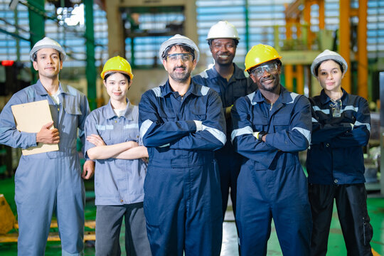 Industrial workers standing with arms crossed in factory, expressing confidence and leadership. Concept of strong teamwork, professional engineers, manufacturing workforce and industrial reliability.