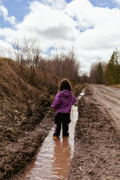 Little girl walking through a deep spring mud puddle
