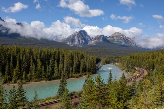 Train Tracks Curving Through Forest Along Mountain River Valley