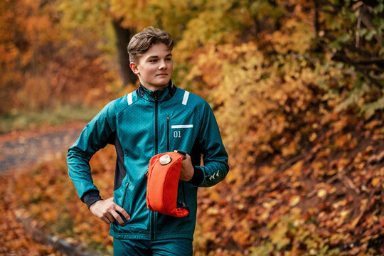 athlete rests and drinks from  hydration pack while jogging in park.