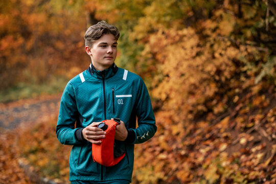 athlete rests and drinks from  hydration pack while jogging in park.