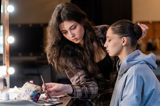 Young makeup artist preparing ballerina backstage