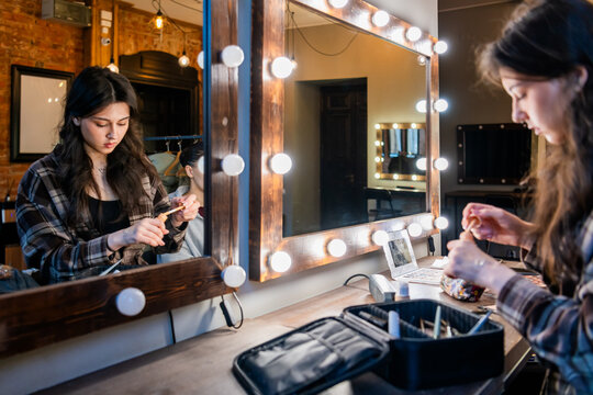 makeup artist prepares to apply liquid foundation in a studio.