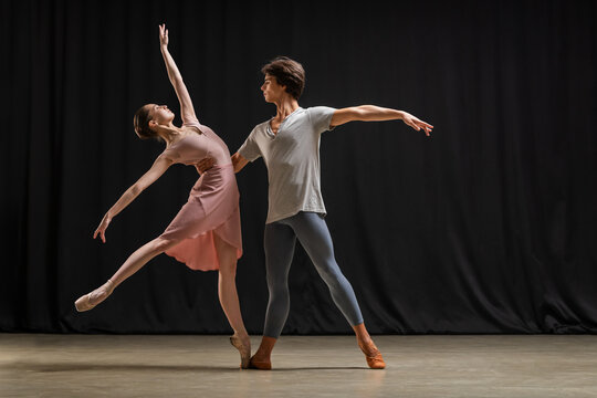 Ballerina and male ballet dancer performing on theater stage.