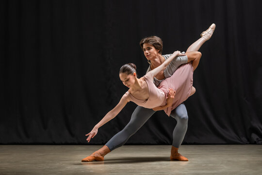 Woman and man professional ballet dancers performing on stage.