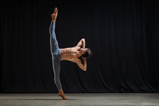 male ballet dancer performs complex choreography on stage.