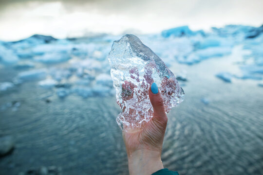 Tourist girl is holding a block of ice in her hand. It stands on