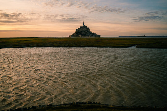 Mont Saint-Michel stands tall against the sunset with water