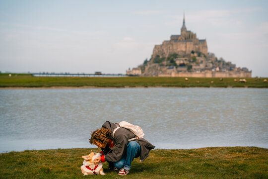 Woman interacts with corgi dog near Mont Saint-Michel in Normandy