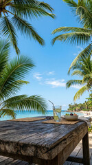 Fototapeta premium Glass of lime water and bowl of fruit on rustic wooden table overlooking tropical beach. Relaxing summer vacation atmosphere at ocean coast. Concept of exotic holiday travel lifestyle.