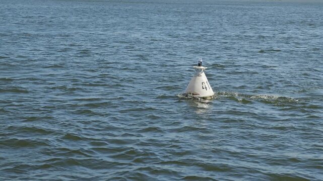 White conical navigation buoy with number 411 floating on deep blue water. Minimalist composition with rippling waves evokes solitude, guidance, and safety on a large river, lake, or sea