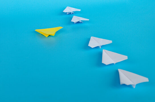 ellow lead paper airplane followed by white planes in a gentle diagonal formation with customizable space for text or ideas.