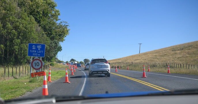 Roadworks ahead. 10km/h temporary speed limit road sign and traffic cones on the road. North Island. New Zealand.